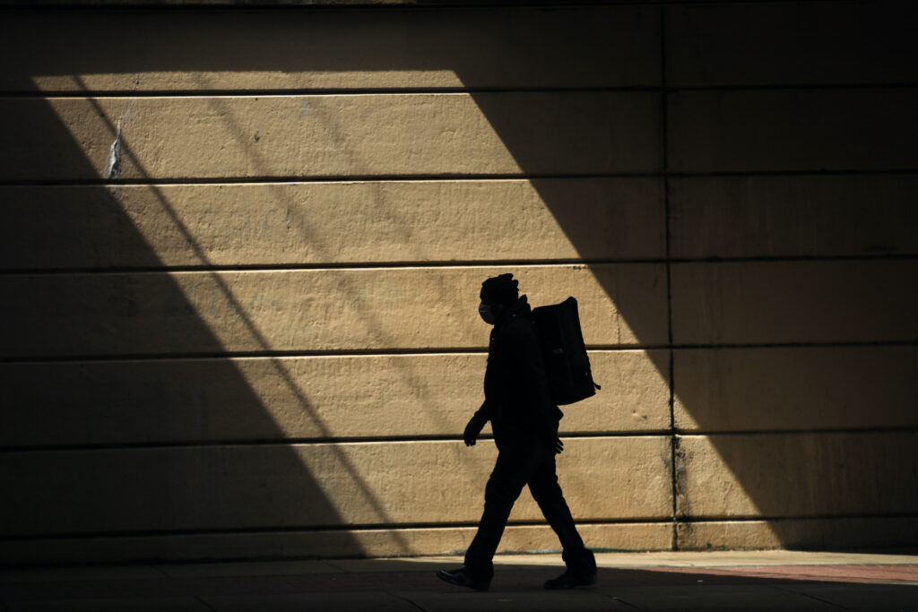 A person wearing a protective face mask as a precaution against the coronavirus walks in Philadelphia, Thursday, April 16, 2020. (AP Photo/Matt Rourke)