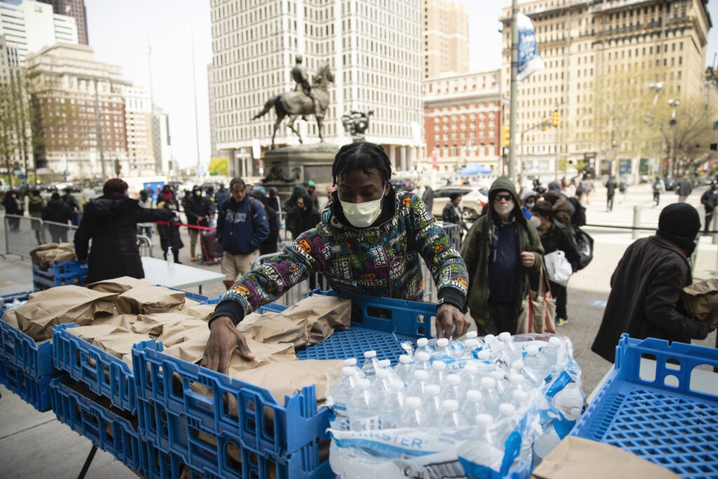 Virus Outbreak Pennsylvania Volunteer Diamon Logan with Broad Street Ministry distributes food as part of a new initiative called Step Up to the Plate, outside City Hall in Philadelphia, Friday, April 17, 2020. The program aims to help those with food insecurity and is a partnership of Broad Street Ministry, Prevention Point Philadelphia, and Project HOME, with the City of Philadelphia. (AP Photo/Matt Rourke)