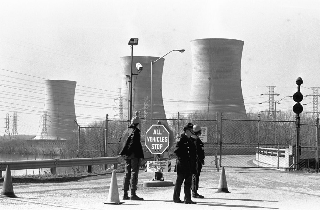 FILE - In this Wednesday, March 28, 1979 file photo, a Pennsylvania state police officer and plant security guards stand outside the closed front gate to the Three Mile Island nuclear power plant near Harrisburg, Pa. after the plant was shut down following a partial meltdown. (AP Photo/Paul Vathis)