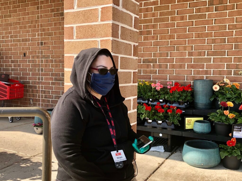IMG_6953 Miriam Casillas stands guard outside the Acme in Pike Creek, making sure shoppers are wearing a mask. (Cris Barrish/WHYY)