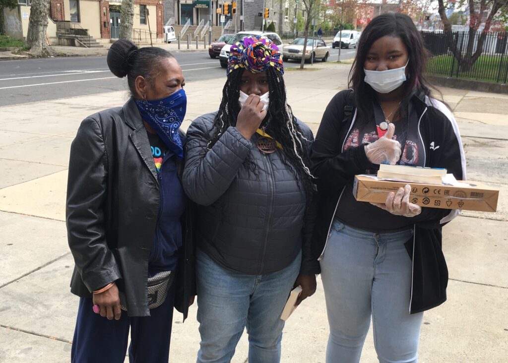 Sayre Neya Foster (right) with a new laptop and her mother and older sister were at Sayre High in West Philadelphia. (Bill Hangley/The Notebook)