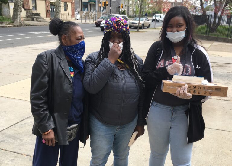 Neya Foster (right) with a new laptop and her mother and older sister were at Sayre High in West Philadelphia. (Bill Hangley/The Notebook)