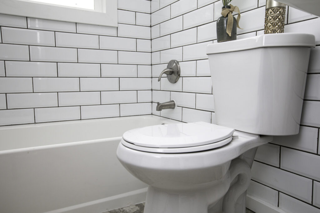 Toilet Shot In Detail In A White Subway Tile Bathroom (Duntrune Studios/BigStock)
