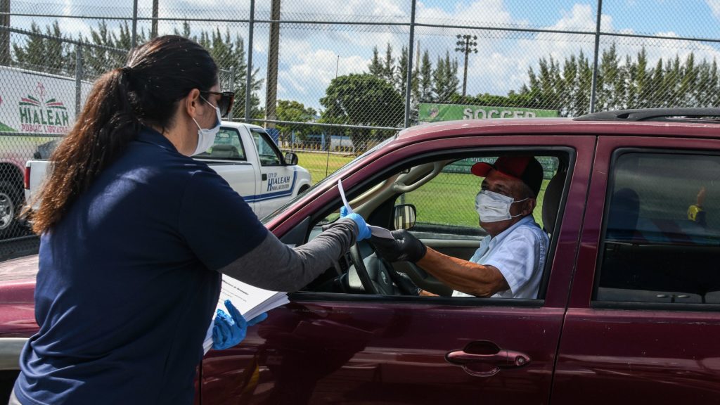 A man collects unemployment forms at a drive-through collection point outside of a library in Hialeah, Fla., on Wednesday. A man collects unemployment forms at a drive-through collection point outside of a library in Hialeah, Fla., on Wednesday. (Chandan Khanna/AFP via Getty Images)