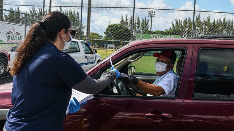 A man collects unemployment forms at a drive-through collection point outside of a library in Hialeah, Fla., on Wednesday. (Chandan Khanna/AFP via Getty Images)