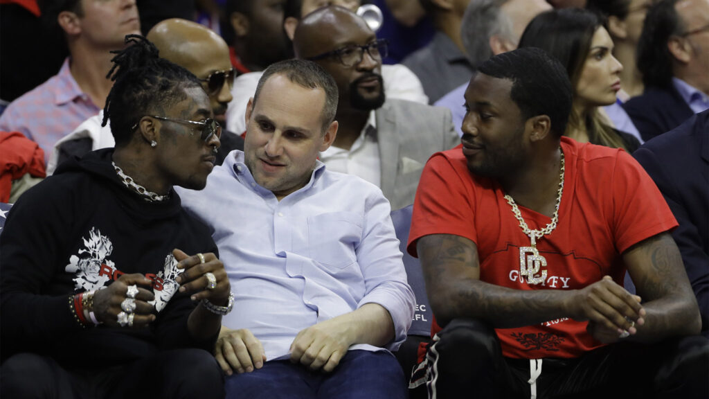 Michael Rubin,Lil Uzi Vert,Meek Mill In this May 7, 2018 photo, Philadelphia 76ers' co-owner Michael Rubin, center, talks with rappers Lil Uzi Vert, left, and Meek Mill during the first half of Game 4 of an NBA basketball second-round playoff series against the Boston Celtics in Philadelphia. Meek Mill had a string of high-profile names support him during a five-month campaign to be freed on bail from prison for probation violations. But the Philly rapper’s biggest advocate was one of his closest friends, the e-commerce entrepreneur who arranged for a helicopter to take Mill from prison to a Sixers' playoff game. Michael Rubin owns Fanatics and co-owns the Sixers and has vowed to tackle criminal justice reform. (AP Photo/Matt Slocum)