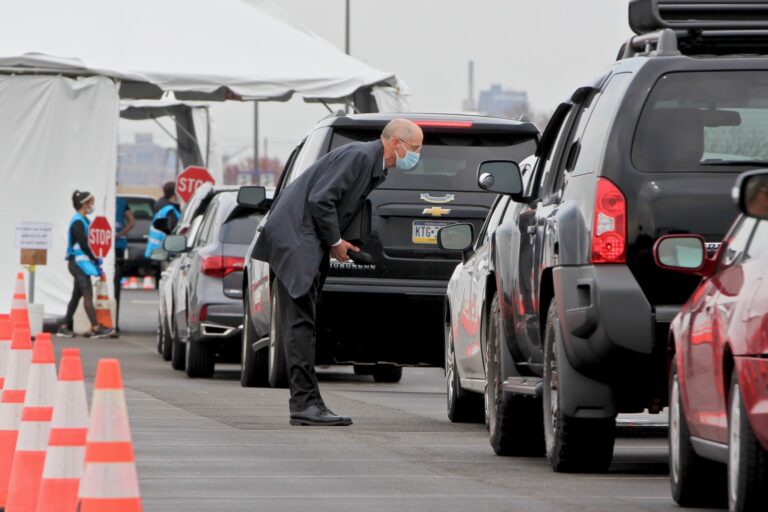 Philadelphia Health Commissioner Thomas Farley walks among cars lined up for coronavirus testing at Citizens Bank Park, pausing to speak with the occupants of each car. (Emma Lee/WHYY)