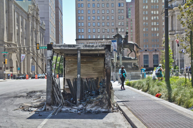Volunteers pick up trash and debris around a burnt out storage container near City Hall in Philadelphia. (Kimberly Paynter/WHYY)