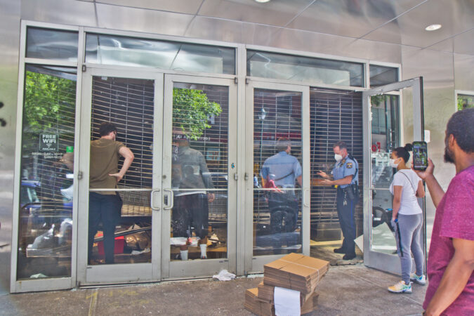 Police officers help AT&T employees secure the storefront in Center City Philadelphia. (Kimberly Paynter/WHYY)
