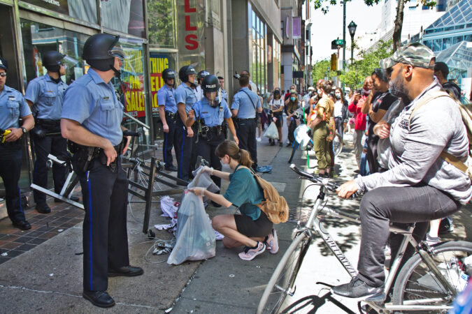 Police officers guard a Modell’s Sporting Goods Store after people tried to run off with more merchandise