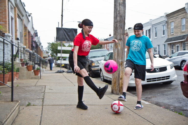 Yvanna, 13, (right), and Emilia, 12, (left) play with soccer balls on their block. (Kimberly Paynter/WHYY)