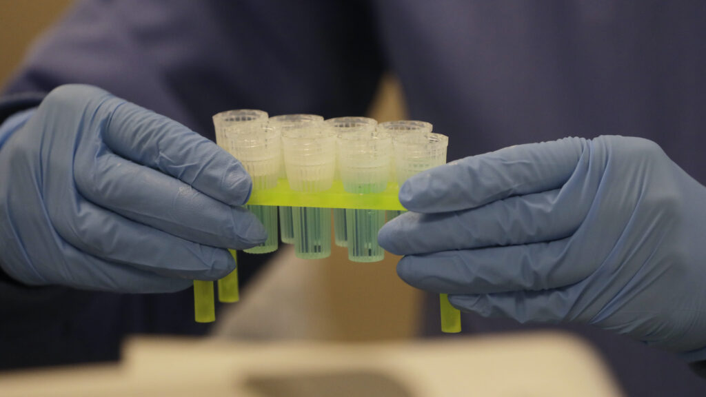 Virus Outbreak Utah In this April 3, 2020, photo, a technician holds blue preservation solution in a clean room where saliva collection devices are assembled at Spectrum DNA in Draper, Utah. The company has developed a test kit to detect the coronavirus in patients' saliva. (AP Photo/Rick Bowmer)
