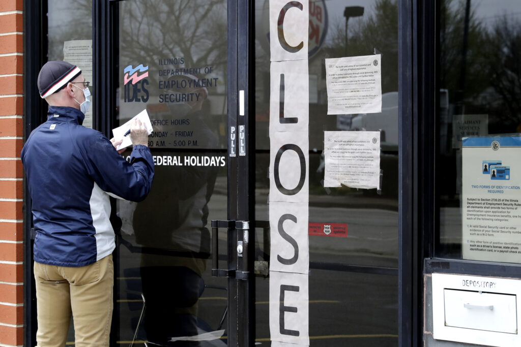 FILE - In this April 30, 2020 file photo, a man writes information in front of Illinois Department of Employment Security in Chicago. U.S. businesses cut an unprecedented 20.2 million jobs in April, an epic collapse with coronavirus outbreak closing the offices, factories, schools, construction sites and stores that propel the U.S. economy. The Wednesday, May 6,  report from payroll company ADP showed the tragic depth and scale of job losses that left no part of the world’s largest economy unscathed.  (AP Photo/Nam Y. Huh, File)
