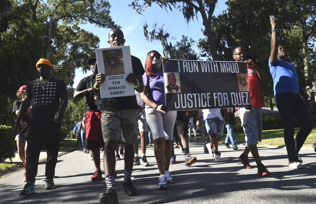 CORRECTION Georgia Chase Deadly Shooting In this Tuesday, May 5, 2020, photo, a crowd marches through a neighborhood in Brunswick, Ga. They were demanding answers in the death of Ahmaud Arbery. (Bobby Haven/The Brunswick News via AP)