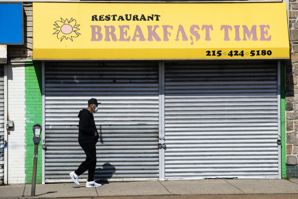 Virus Outbreak Pennsylvania A person wearing a protective face mask as a precaution against the coronavirus walks past a shuttered business in Philadelphia, Thursday, May 7, 2020. (AP Photo/Matt Rourke)