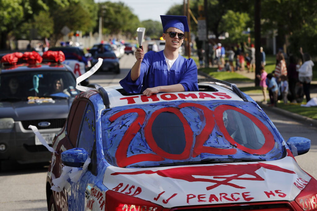 Virus Outbreak Texas Graduation Parade Thomas Harden rings a cowbell as he stands up through the vehicles sun roof waving a supporters during a neighborhood parade honoring 2020 student graduates from both J.J. Pearce and Richardson High Schools in Richardson, Texas, Saturday, May 9, 2020. (AP Photo/Tony Gutierrez)