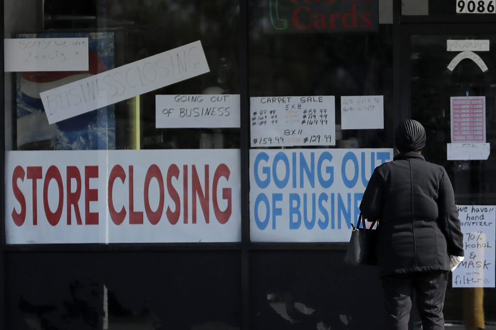 Virus Outbreak Illinois Unemployment A woman looks at signs at a store closed due to COVID-19. (AP Photo/Nam Y. Huh)