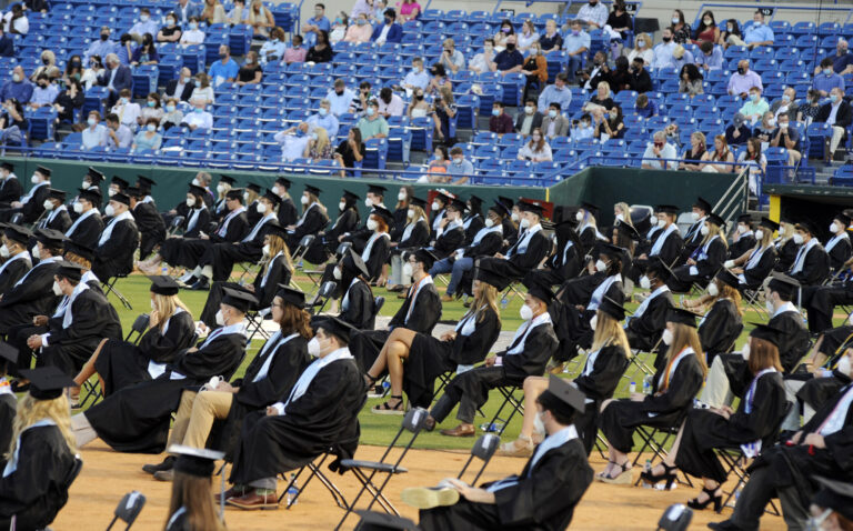 Senior class members and spectators, most of them wearing masks, attend the graduation ceremony of Spain Park High School in Hoover, Ala., Wednesday, May 20, 2020. Health officials say usual graduation ceremonies could endanger the public health by promoting the spread of disease. But school officials say they're using social distancing guidelines and abiding by state health rules. (AP Photo/Jay Reeves)