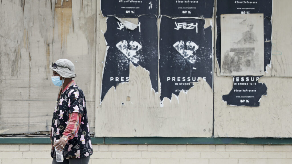 Virus Outbreak Ohio Economy A woman walks past a boarded up business, Thursday, May 28, 2020, in East Cleveland, Ohio. (AP Photo/Tony Dejak)