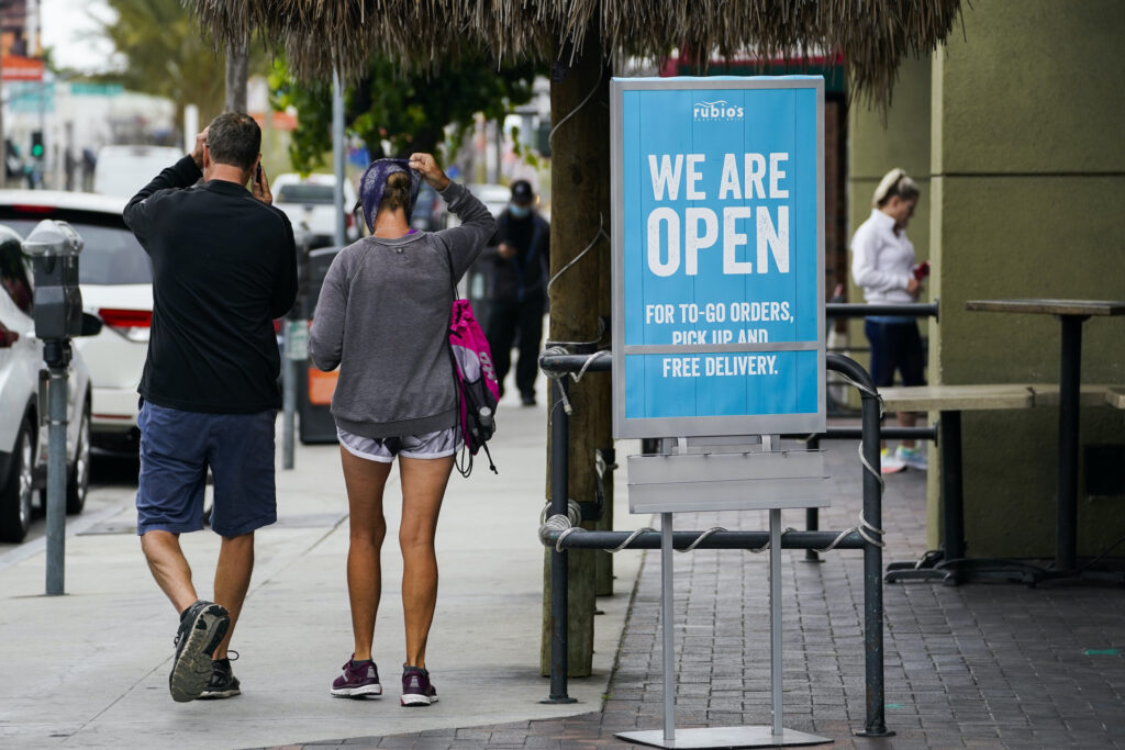 Customers walk past an open sign at Rubio's Coastal Grill