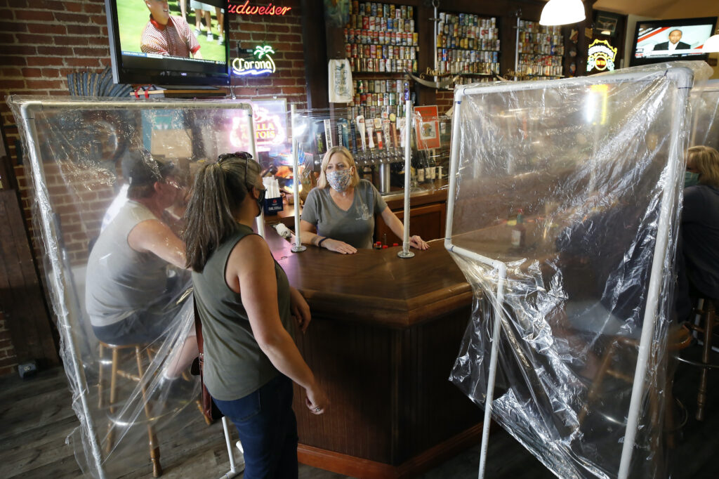 Sheila Kelly stands behind makeshift barriers as she helps patrons at her restaurant
