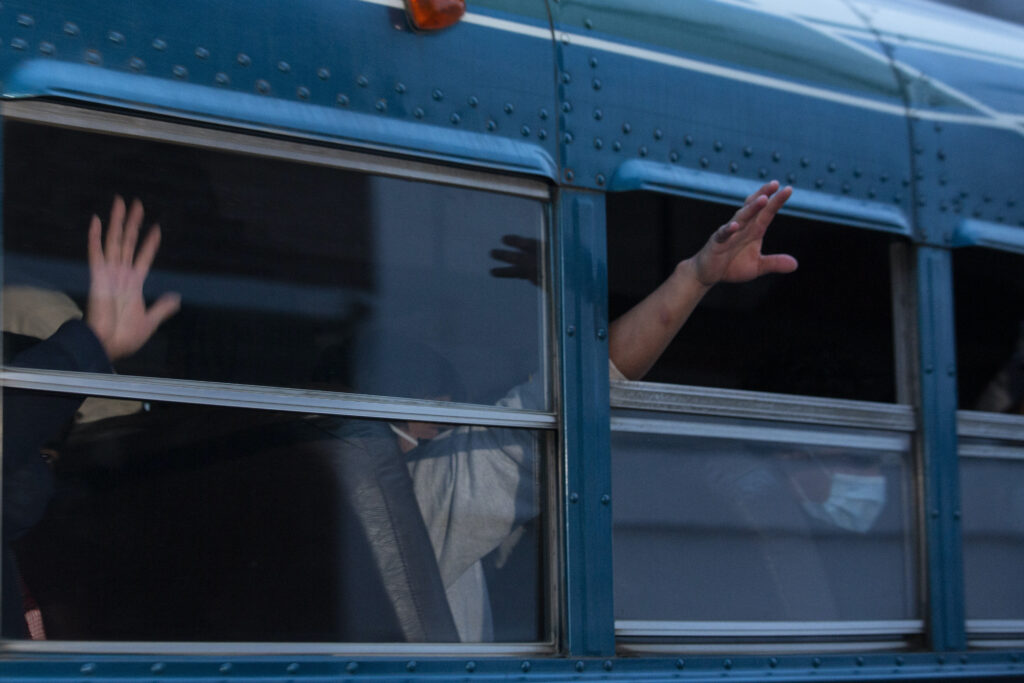 Virus Outbreak Migrant Children Guatemalans deported from the U.S., wave from a bus.
