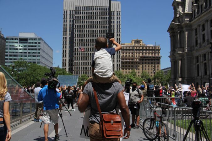 G. Lamar Stewart of Philadelphia and his 5-year-old son, G. Lamar Jr., join the protest at Dilworth Park. (Emma Lee/WHYY)
