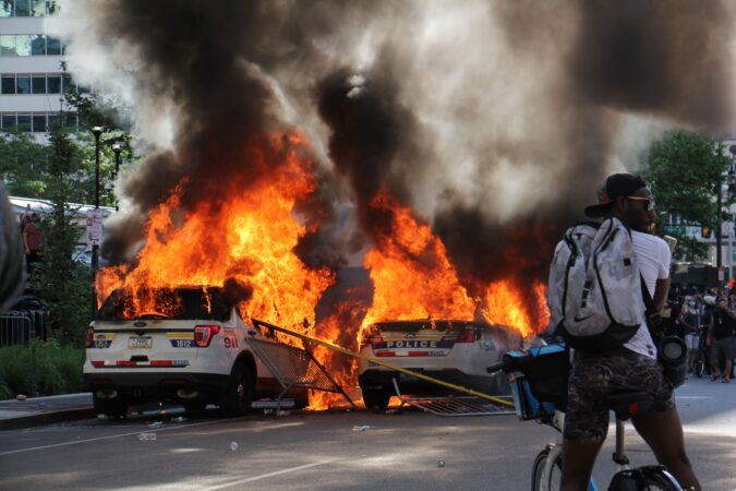 Police cars burn at Broad and JFK in Center City.