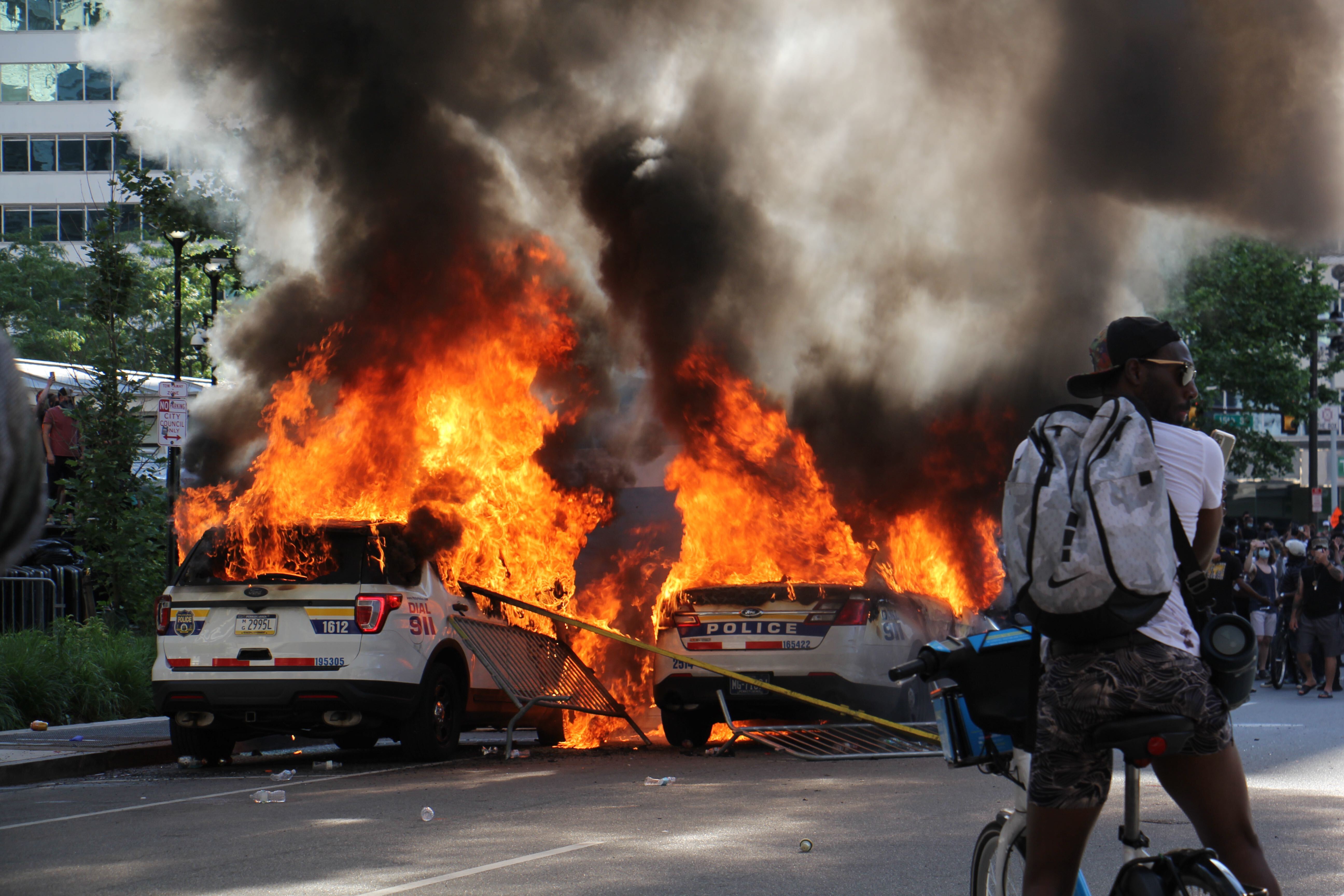 Police cars burn at Broad and JFK in Center City.