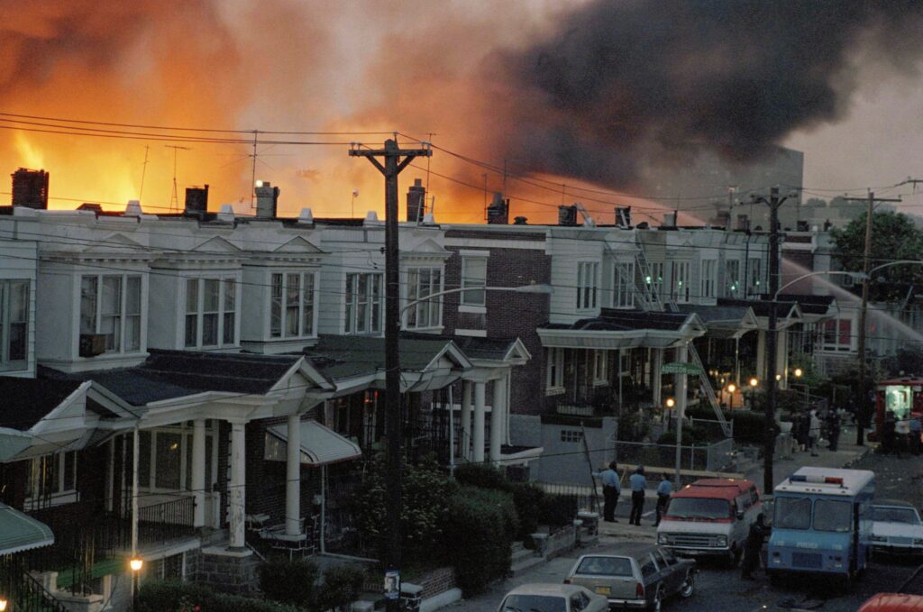 Philadelphia MOVE Bombing Anniversary In this May, 1985 file photo, scores of rowhouses burn in a fire in the west Philadelphia neighborhood. Police dropped a bomb on the militant group MOVE's home on May 13, 1985 in an attempt to arrest members, leading to the burning of scores of homes in the neighborhood. (AP Photo, File)