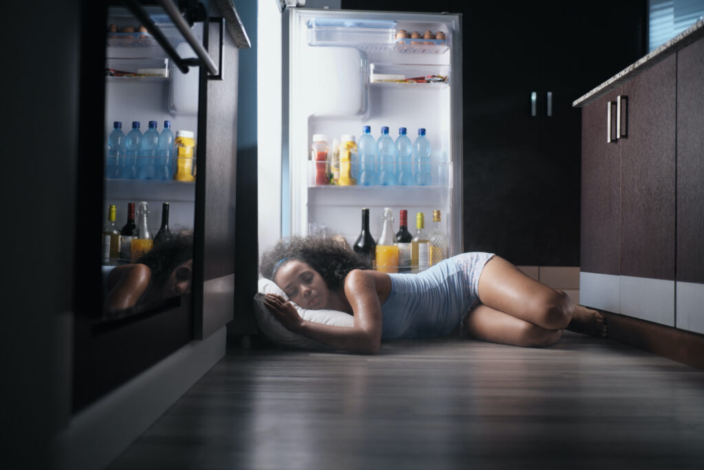 Young Hispanic Woman Suffering For Summer Heat And Lack Of Air Conditioning At Home. Black Girl Cove Weather forecasts predict temperatures higher than normal for this summer. With public pools closed for the season and limited access to air-conditioned public spaces, keeping cool will be a challenge. (Chinnapong/Big Stock)