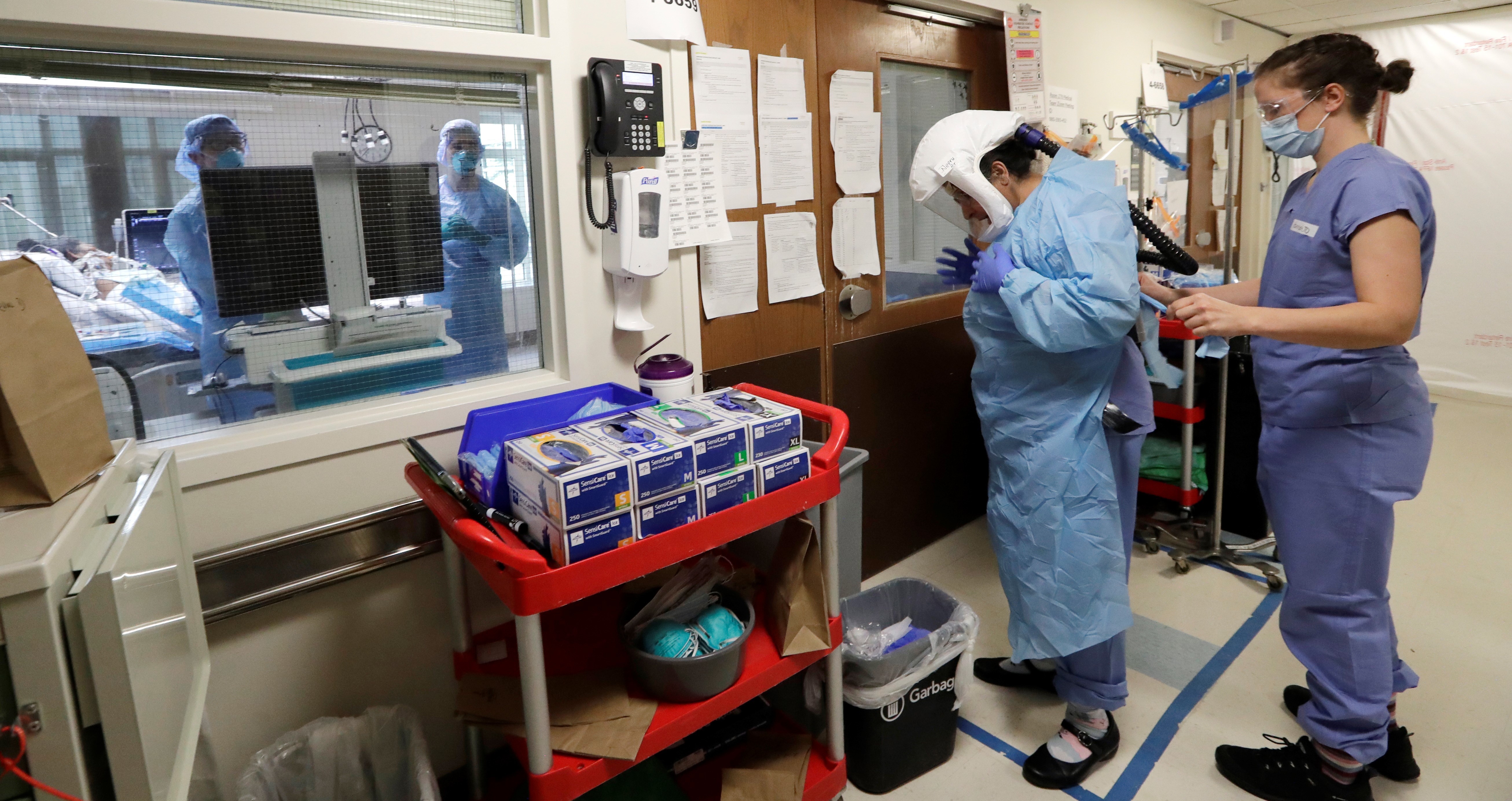 A medical worker is assisted into PPE