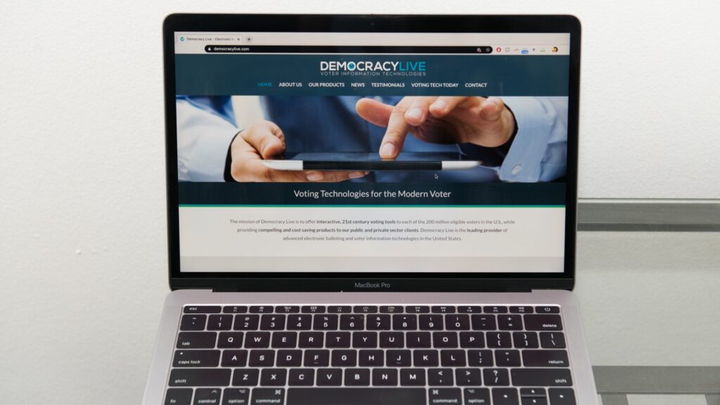 democracy-live_wide-1920×1080 The Democracy Live home page is displayed on an Apple laptop computer. The company is administering a ballot return system for disabled voters in West Virginia, Delaware, and potentially New Jersey. (Courtesy of Democracy Live)