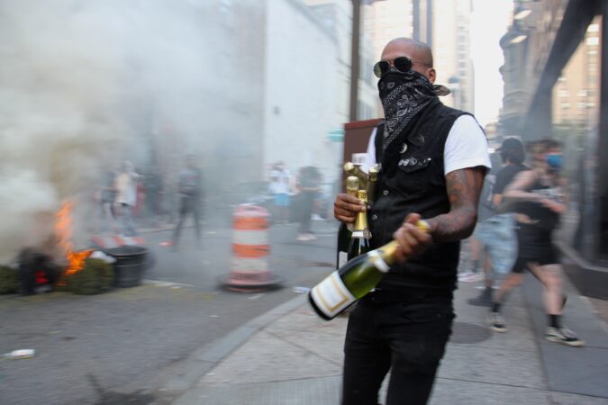 A looter leaves Marathon bar at 16th and Samson with arms full of champagne