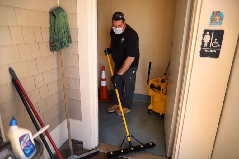 Town worker Steve Crowley washes and disinfects the public restroom at Mayflower Beach, in Dennis, Mass., last week. As stay-at-home restrictions are lifting, many people are concerned about using public restrooms. (John Tlumacki/The Boston Globe via Getty Images)