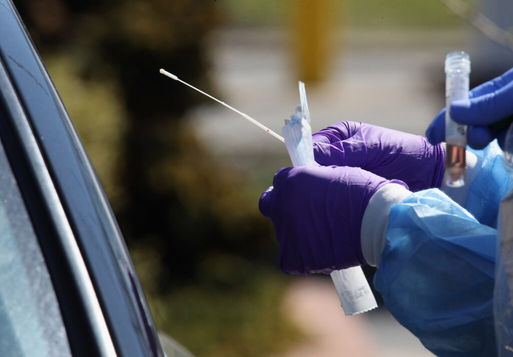 Medical workers prepare to use a swab to administer a coronavirus test at a drive-through center on March 21 in Jericho, N.Y. Medical workers prepare to use a swab to administer a coronavirus test at a drive-through center on March 21 in Jericho, N.Y. (Bruce Bennett/Getty Images)