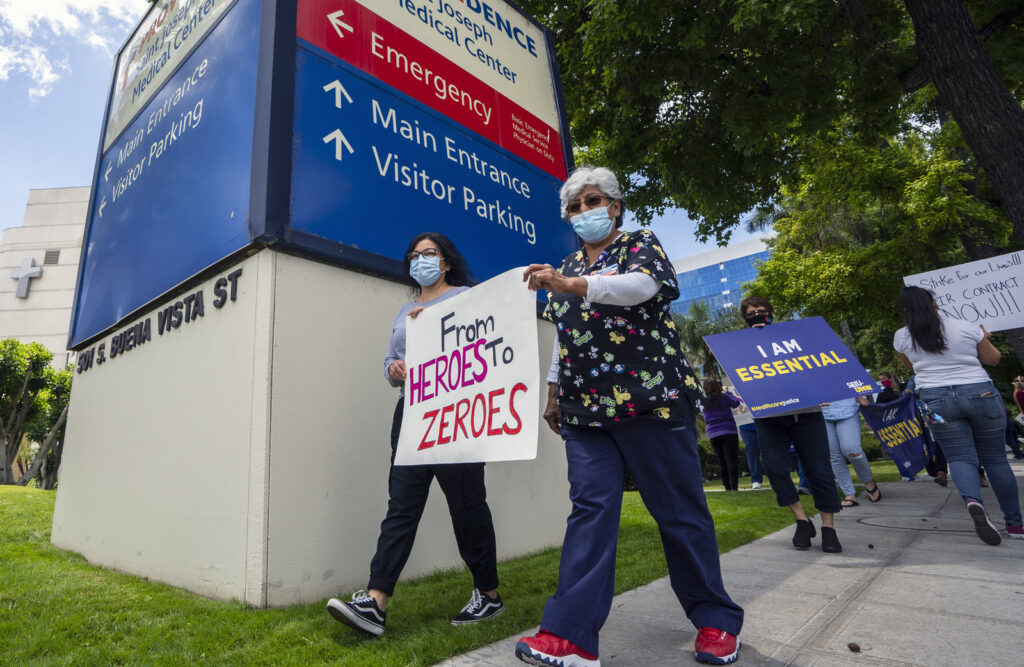 Health care workers hold a placard that says From Heroes to Zeroes during a protest