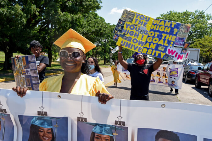 During the parade on June 26, Camden High graduate Zanabria Harris, 18, carries a banner imprinted with photos of Camden graduates.  (Photo by April Saul for WHYY)
