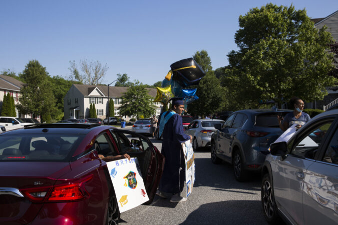 Bryson accepts balloons and a sign from a family member who attended his drive by graduation party on June 9, 2020. (Rachel Wisniewski for Keystone Crossroads)