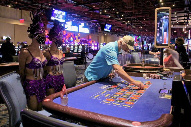 Bob Mills of Wenonah, N.J., places a bet at Harrah's Philadelphia, attended by showgirls Vanessa Harkins and Angel Simpkins. (Emma Lee/WHYY)