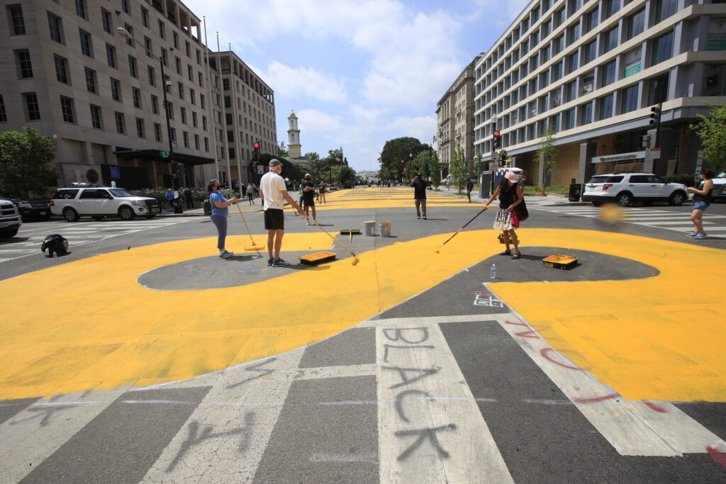 City workers and activists paint the words Black Lives Matter in enormous bright yellow letters on the the street leading to the White House, Friday, June 5, 2020, in Washington.(AP Photo/Manuel Balce Ceneta)