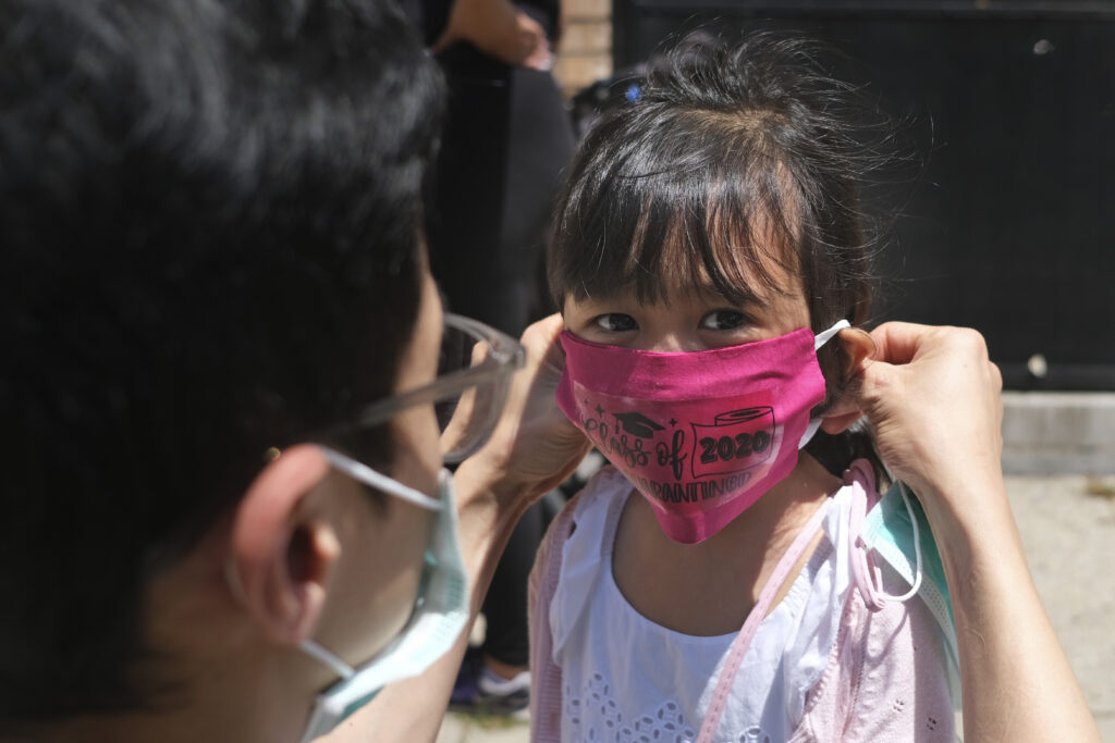 Virus Outbreak New Jersey Olivia Chan's father helps her put on a face mask