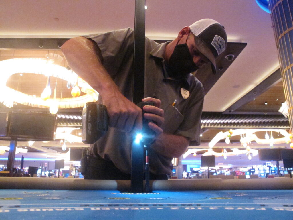 Virus Outbreak Atlantic City Casinos In this June 24, 2020 photo, Dean Loveland, a worker at the Hard Rock casino in Atlantic City N.J., installs plexiglass barriers between player positions at a card table at the casino a week before it was to reopen amid the coronavirus outbreak. Smoking, drinking and eating will all be prohibited when Atlantic City's casinos reopen after being shut for three months due to the coronavirus outbreak under rules imposed by New Jersey Gov. Phil Murphy on June 29, 2020. (AP Photo/Wayne Parry)