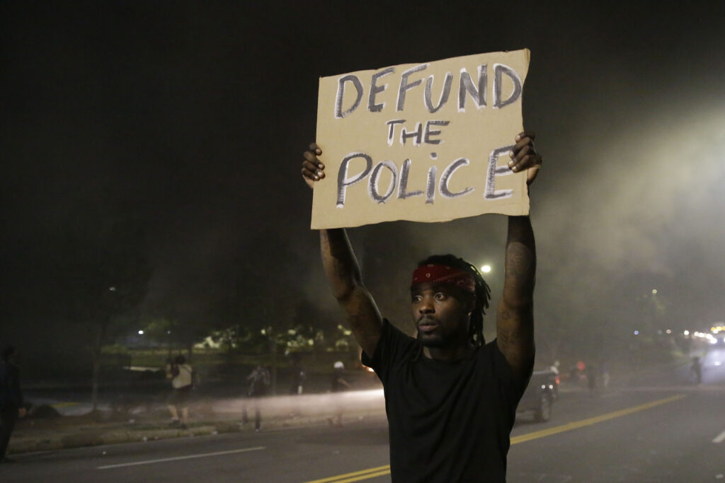 A man holds up a sign amid smoke of a fire during a protest