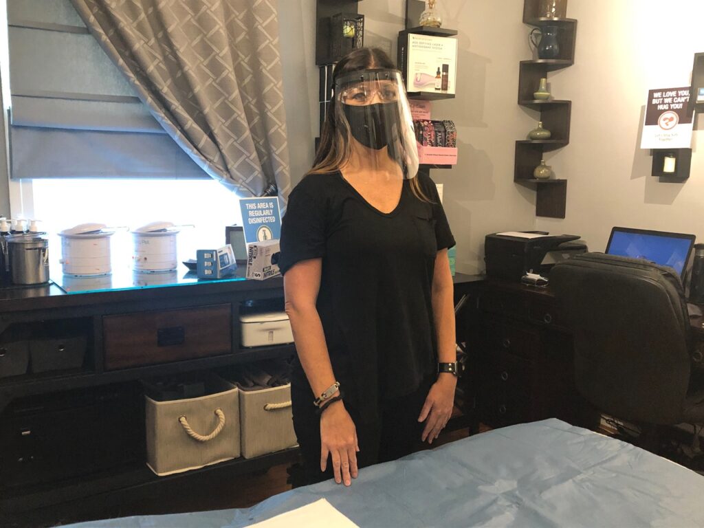 IMG_7310 Aesthetician Jen Allegretti wears the face mask and shield she will use while working with clients. (Cris Barrish/WHYY)