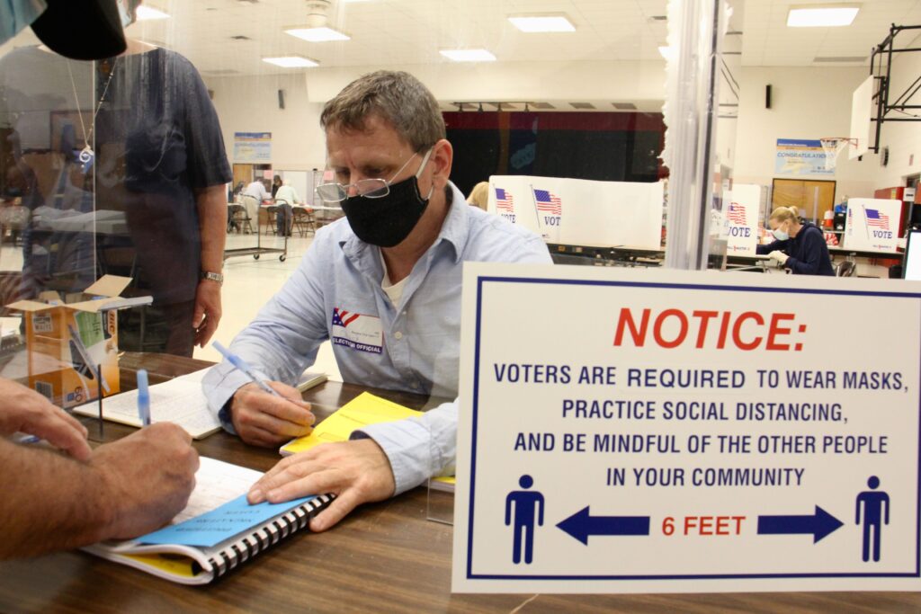 Image from iOS (53) Poll worker Chuck Kellander interacts with voters through a plexiglass screen at Belmont Hill Elementary School in Bensalem, Bucks County. (Emma Lee/WHYY)