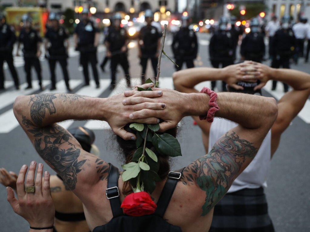 Protesters kneel in front of New York City police officers before being arrested for violating curfew on Wednesday. Protesters kneel in front of New York City police officers