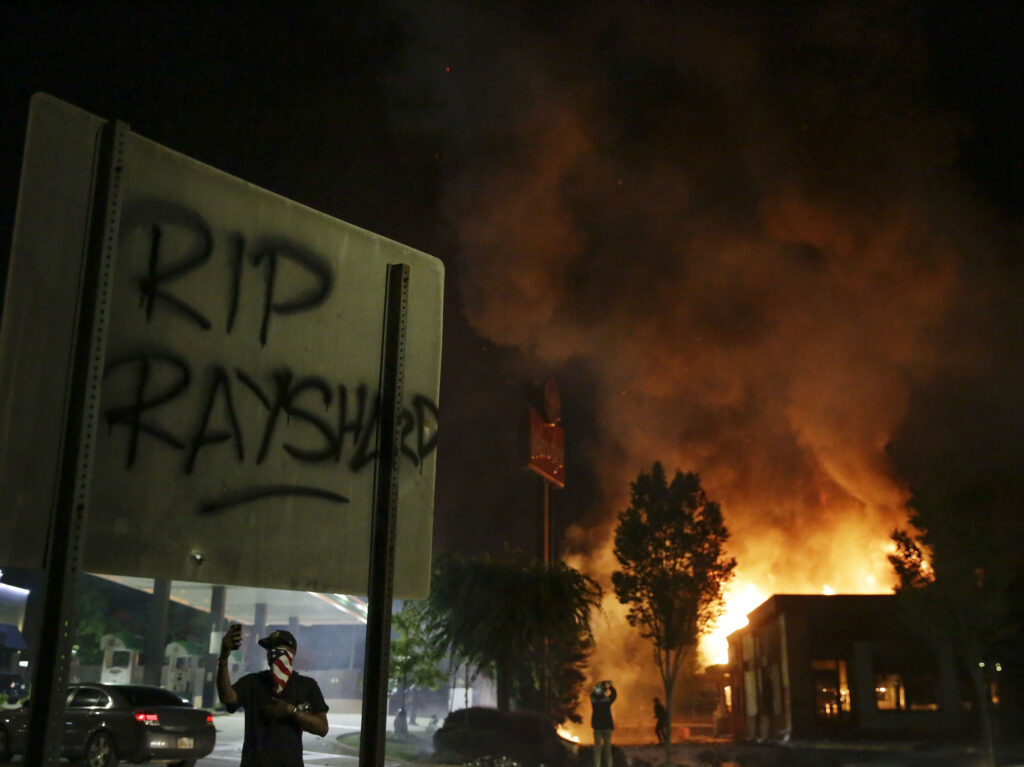 “RIP Rayshard” is spray-painted on a sign as flames engulf a Wendy’s restaurant during protests in Atlanta on Saturday over the death of Rayshard Brooks.