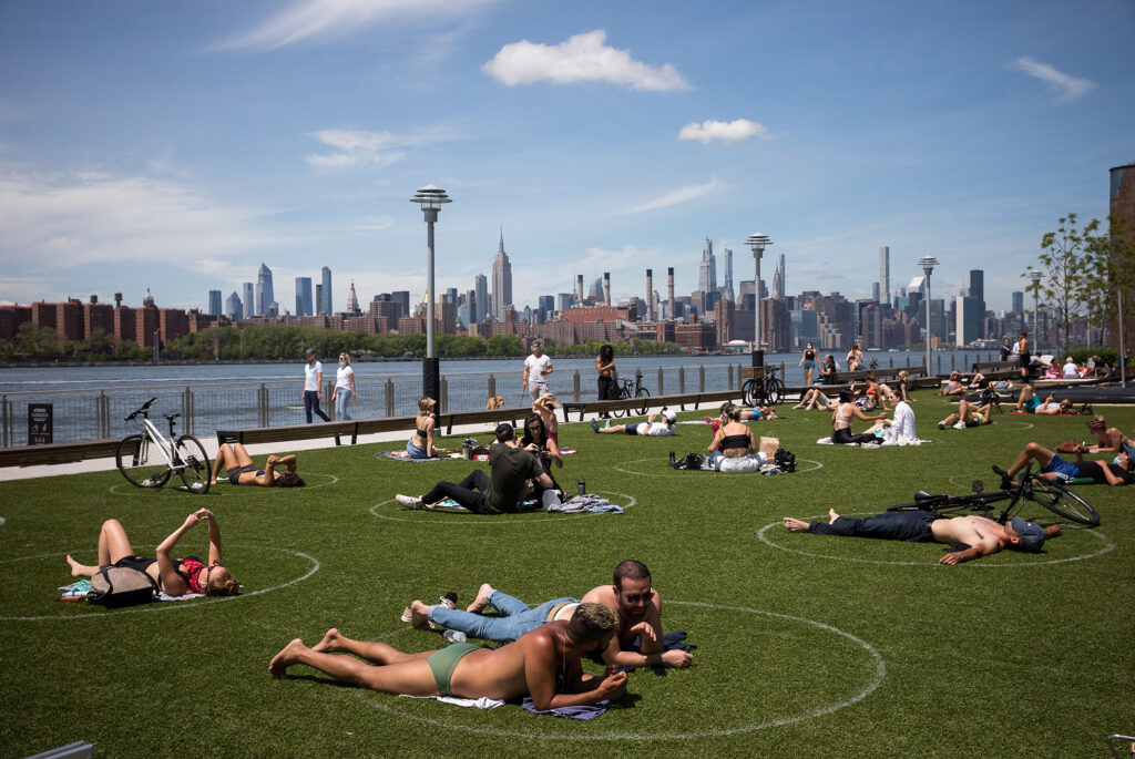 People rest inside social distancing markers at Domino Park in the Brooklyn borough of New York in late May. Stay-at-home orders in New York helped to lower the state’s “reproduction number,” which estimates how many people one sick person could infect with the coronavirus. People rest inside social distancing markers at Domino Park in the Brooklyn borough of New York in late May. Stay-at-home orders in New York helped to lower the state's