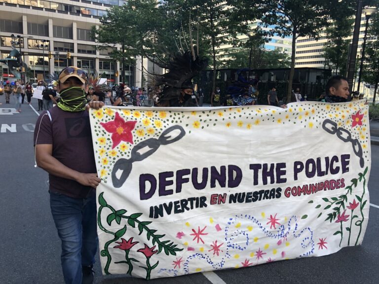 Activists at a rally in Center City hold up a sign demanding the mayor defund the PPD